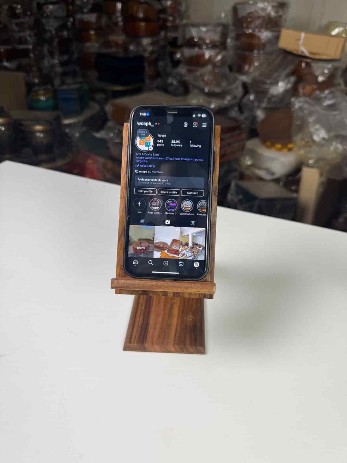 Handcrafted wooden mobile stand holding a smartphone on a desk